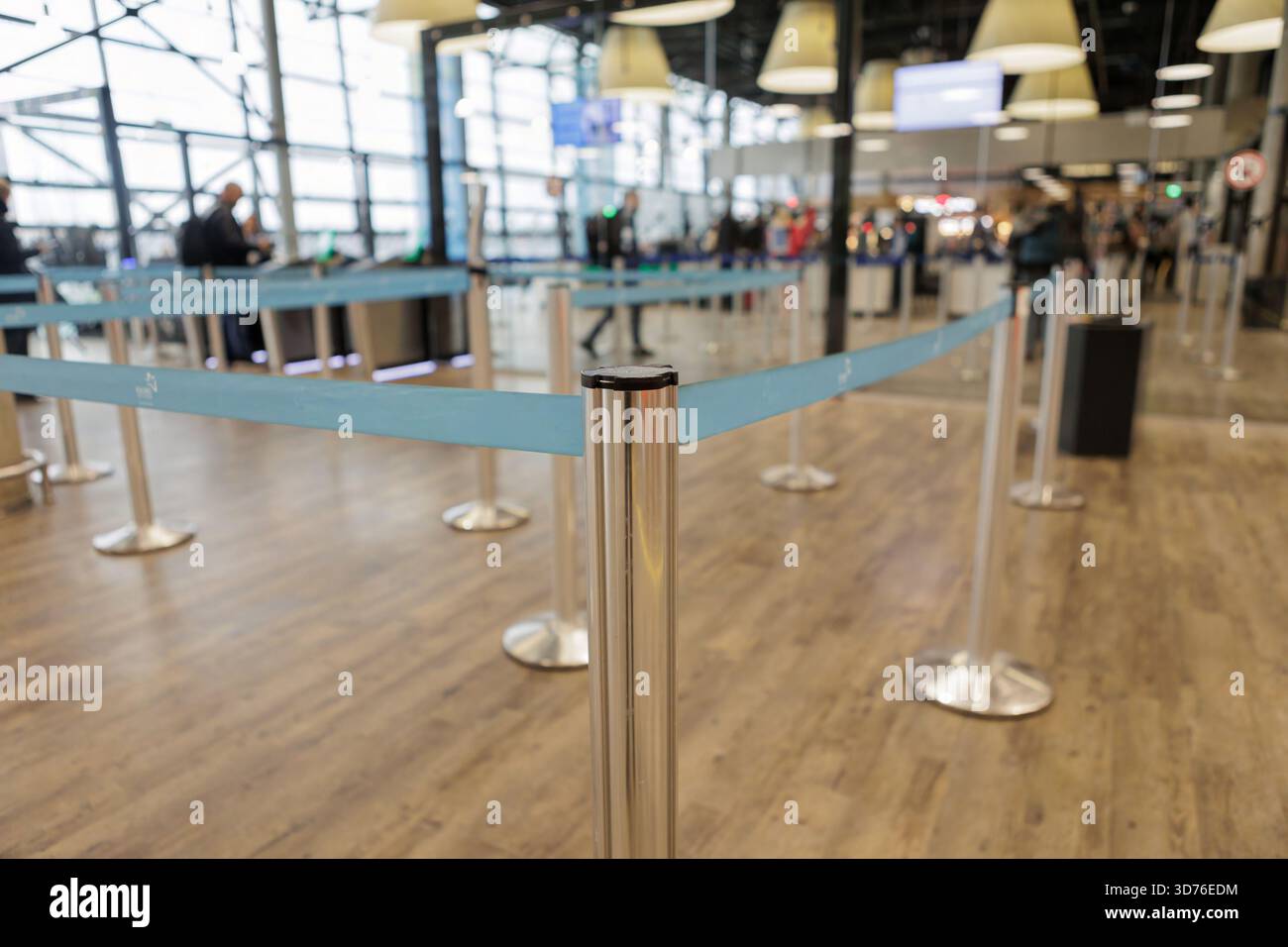 Blaue Warteschlangenbarrieren im leeren Sicherheitsbereich des Flughafens mit Personen im Hintergrund. Hochwertige Fotos Stockfoto