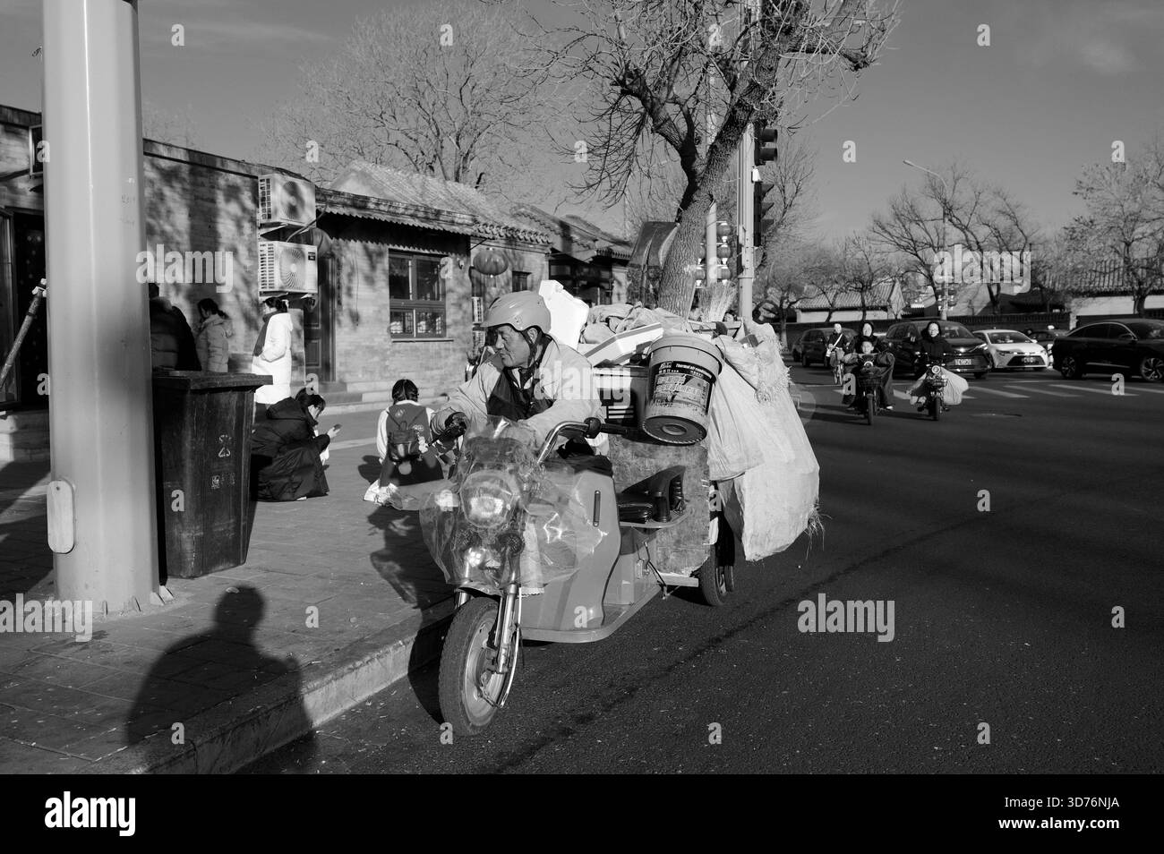 Müllmann steuert im Winter einen überladenen Roller durch eine Straße in peking, in Schwarz-weiß gefangen Stockfoto