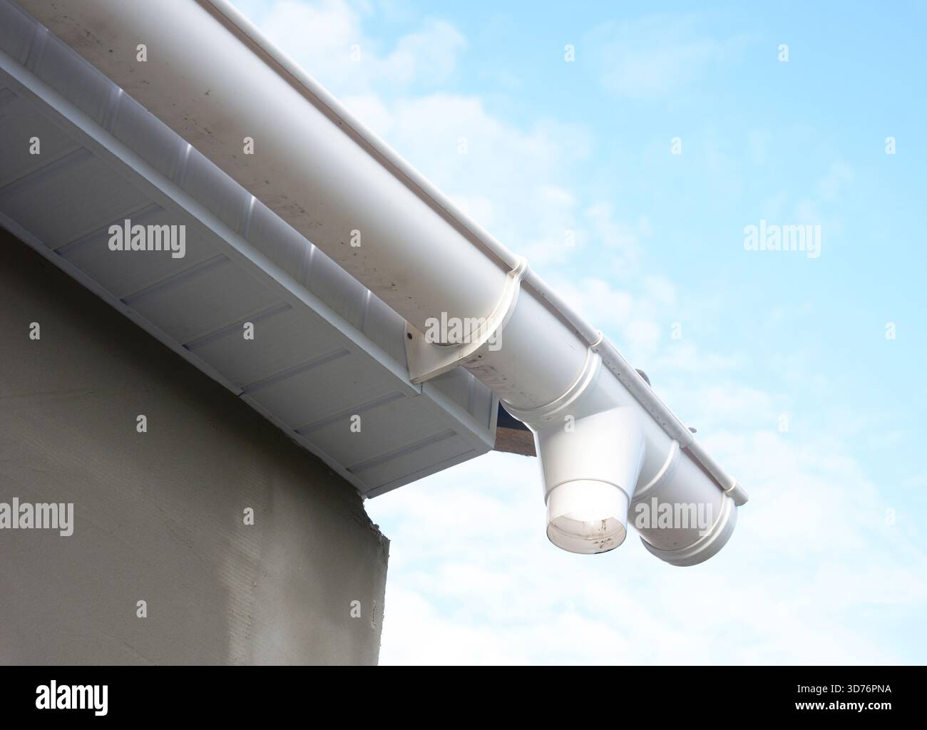 Die Abbildung zeigt eine Nahaufnahme einer weißen PVC-Dachrinne, die am Rand eines Hauses installiert ist. Zu den sichtbaren Elementen gehören die Dachrinne und die Dachrinne Stockfoto