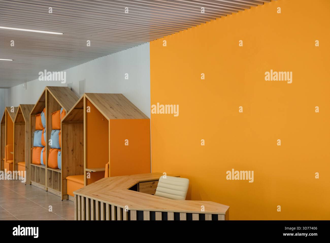 Der helle und fröhliche Rezeptionsbereich ist mit orangefarbenen Wänden und Holzmöbeln ausgestattet. Stockfoto