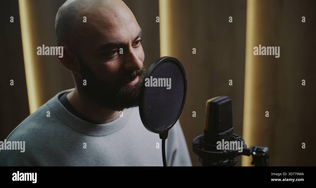 Nahaufnahme eines erfahrenen Dubbing-Schauspielers, der dynamische Dialoglinien aufzeichnet. Face Zeigt Kraftvolle, Kontrollierte Ausdrucksformen Neigen Sich Zum Studio-Mikrofon Und Formen Den Stimmton Mit Präzision Und Emotionaler Tiefe. Stockfoto