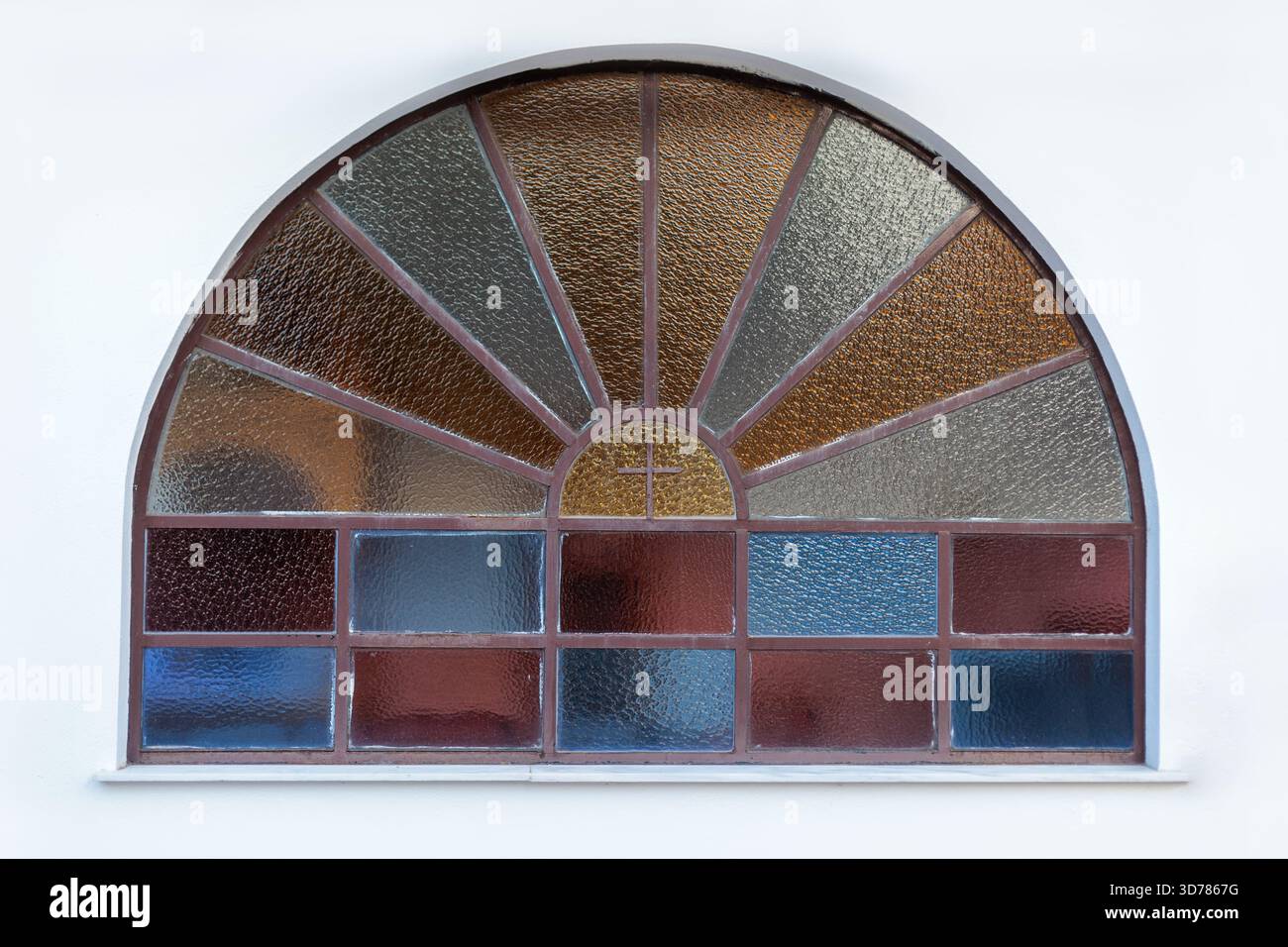 Gebogenes Buntglasfenster mit Kreuzmuster in einer Kirchenfassade Stockfoto