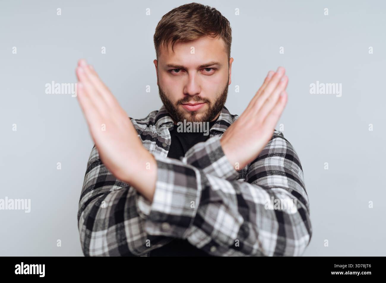 Das Porträt des jungen Mannes lehnt die Vorstellung mit gekreuzten Armen fest ab und stellt eine starke Haltung der Ablehnung auf weißem Hintergrund dar Stockfoto