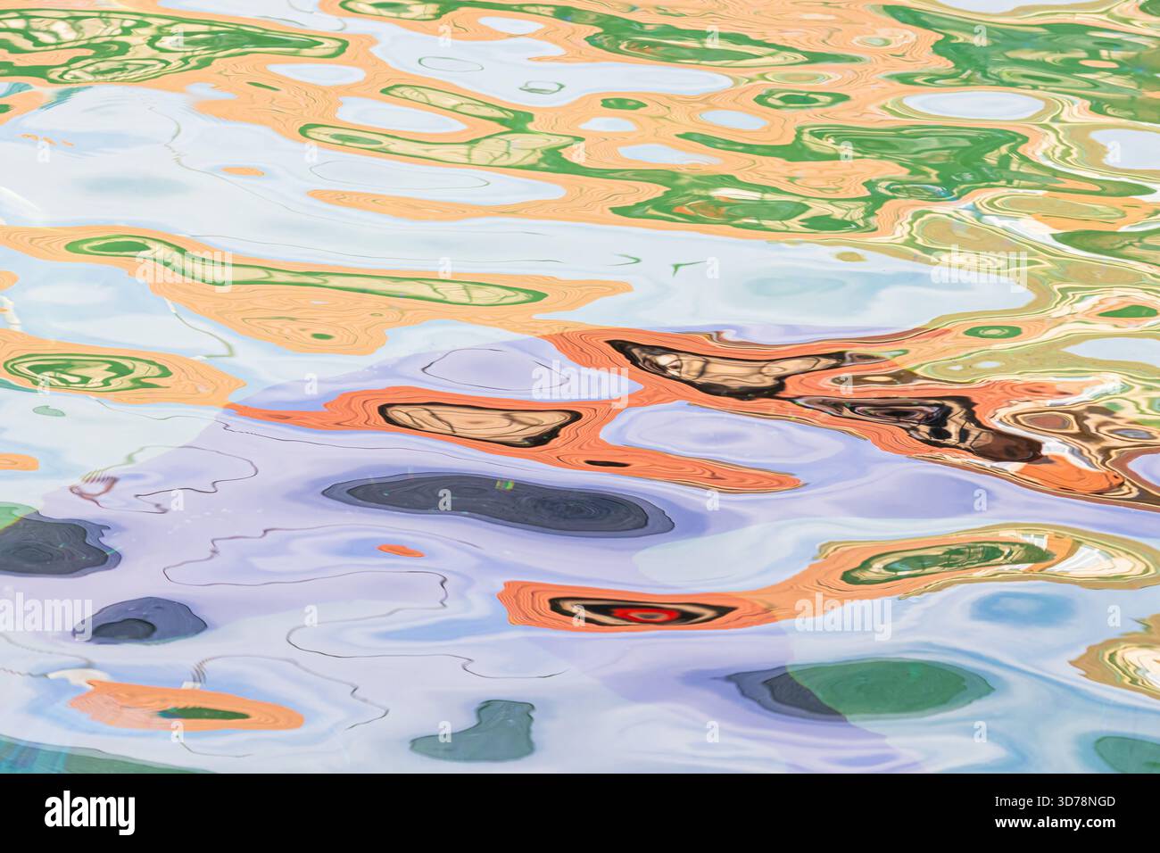 Abstraktes Muster aus leuchtenden orange, grünen und lila Farben reflektiert auf der sich kräuselnden Oberfläche des Wassers und erzeugt eine farbenfrohe, flüssige Textur. Stockfoto