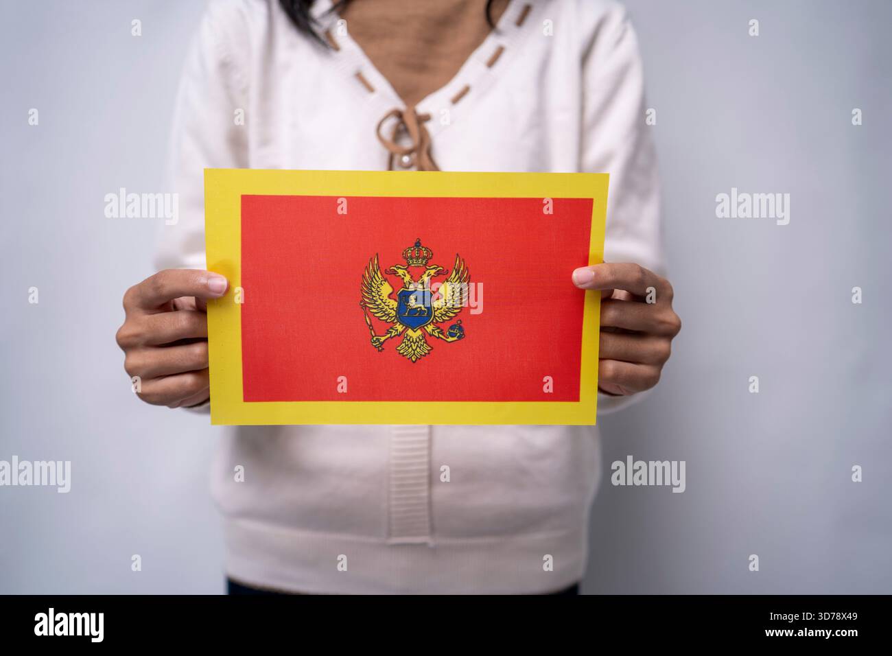 Person, Die Die Nationalflagge Montenegros Vor Neutralem Hintergrund Hält Stockfoto