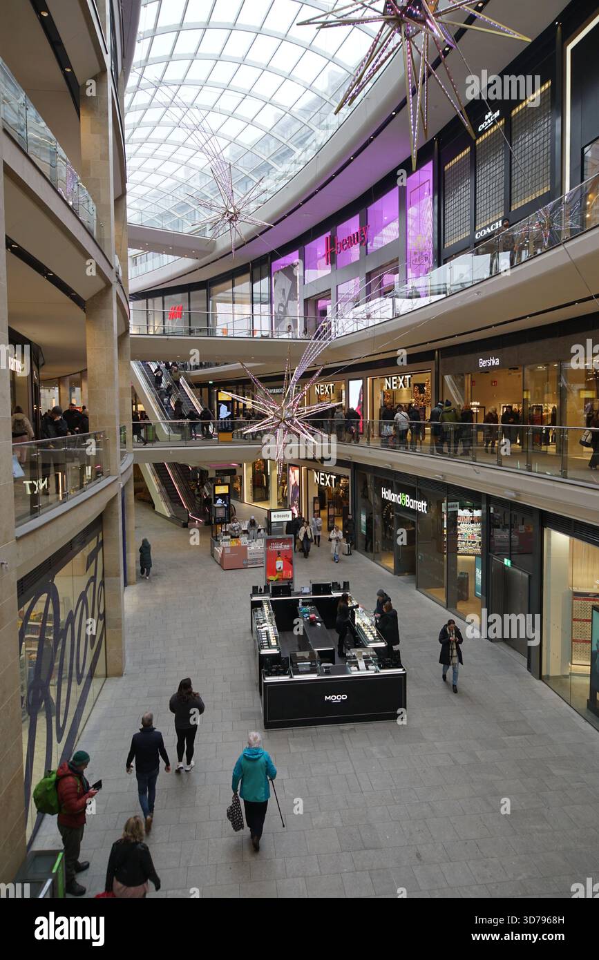 Innenblick auf ein modernes Einkaufszentrum mit mehreren Etagen, Geschäften und dekorativer Beleuchtung. Edinburgh, Schottland Stockfoto