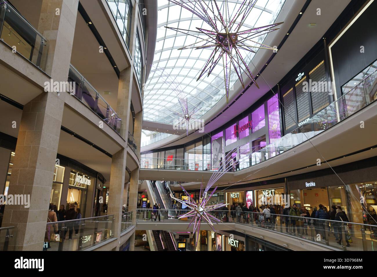 Innenblick auf ein modernes Einkaufszentrum mit mehreren Etagen, Geschäften und dekorativer Beleuchtung. Edinburgh, Schottland Stockfoto