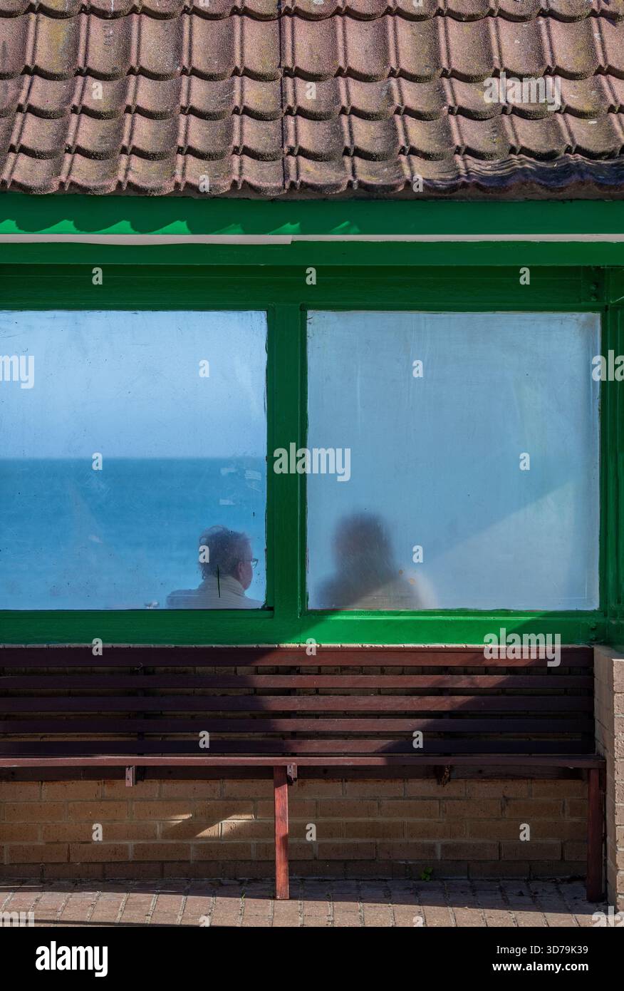 Silhouette eines Paares, das in einem alten Schutzhaus am Strand oder am Meer in Shanklin an der Küste der isle of wight UK sitzt Stockfoto