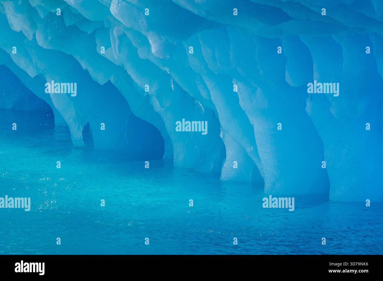 Tropfendes blaues Eismuster aus Erosion durch Meerwasser auf der Basis des schmelzenden Eisbergs im Arktischen Ozean bei Svalbard/Spitzbergen, Norwegen Stockfoto