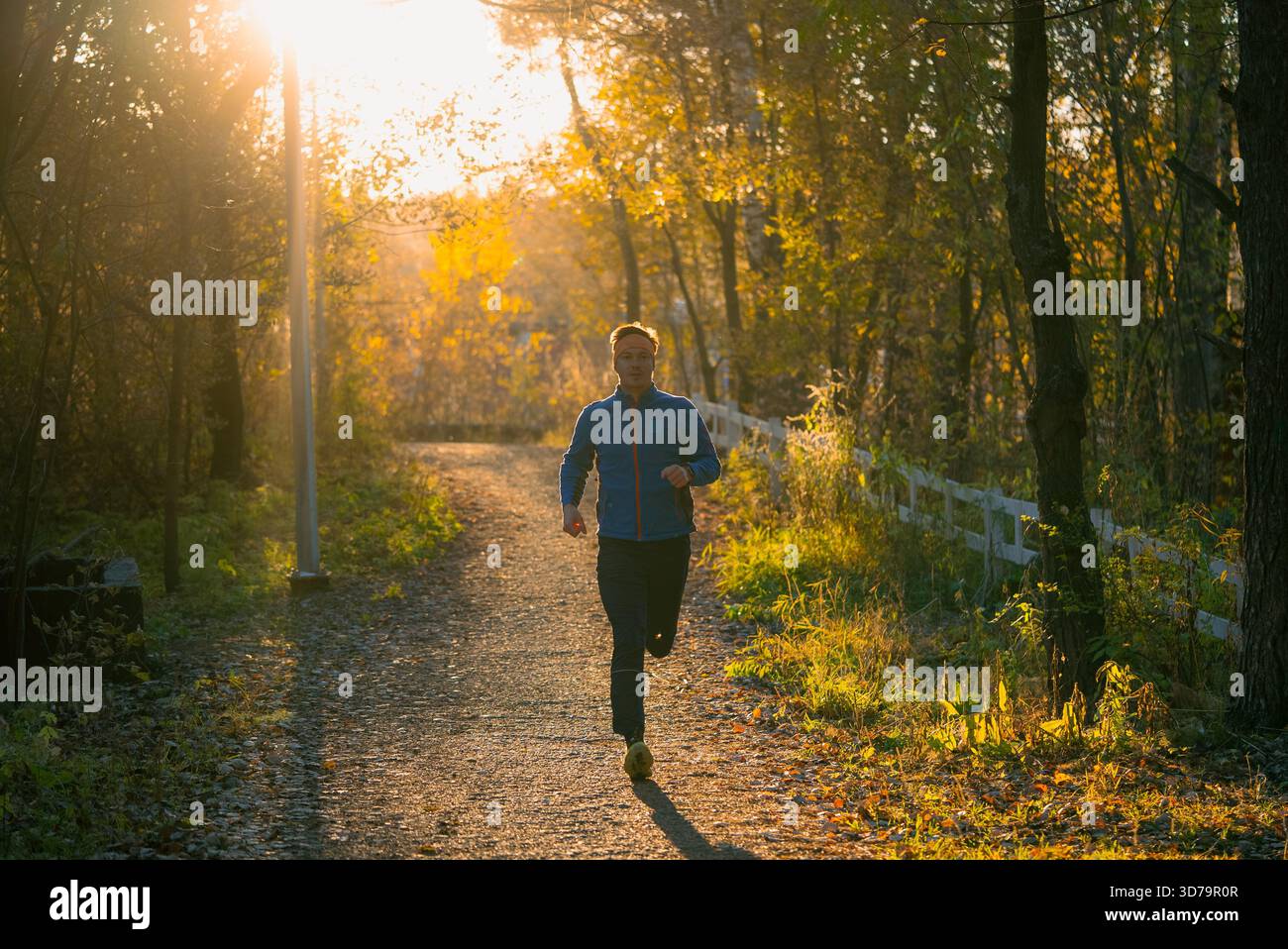 Mann, der an einem Herbstmorgen auf einem Parkweg läuft, konzentriert sich auf regelmäßiges Workout, körperliche Bewegung und das Erreichen persönlicher Fitnessziele an der frischen Luft und verbindet sich mit Natur und Wellness Stockfoto