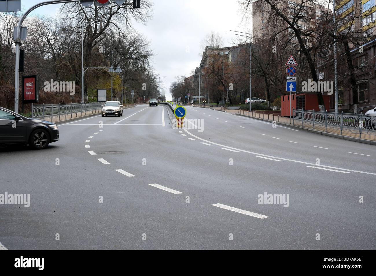 Autos fahren entlang einer leeren Straße mit bewölktem Himmel. November 2025 Kiew, Ukraine Stockfoto