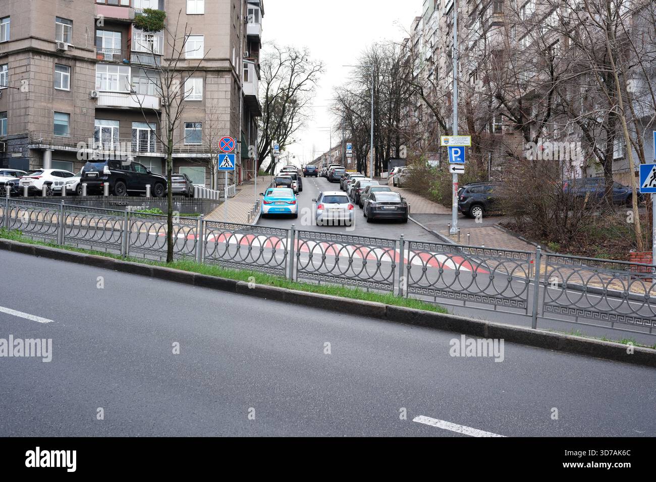 Autos parken entlang der Straße, während die Leute auf dem Bürgersteig in der Nähe spazieren gehen. November 2025 Kiew, Ukraine Stockfoto