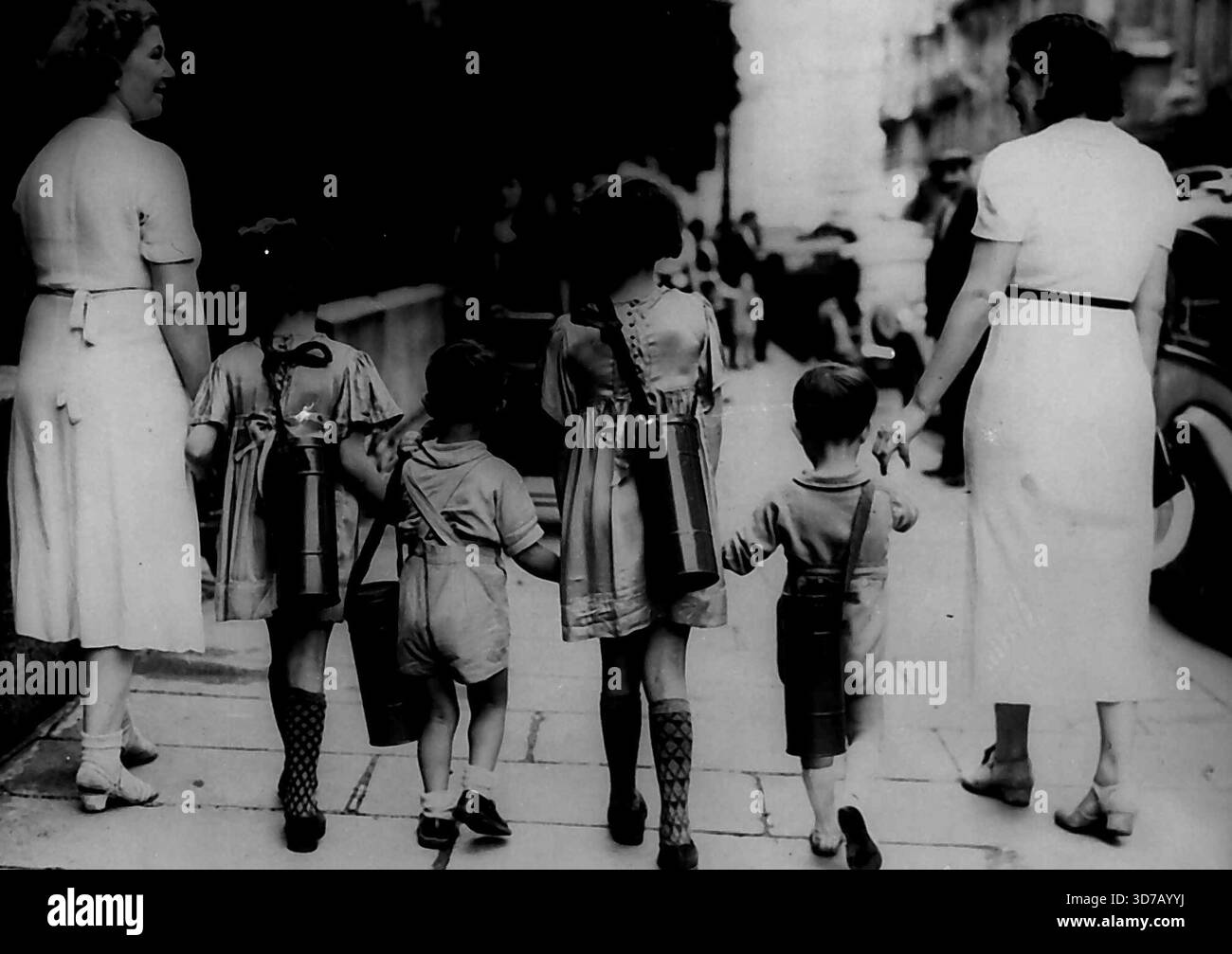 Paris Kinder Erhalten Ihre Gasmasken -- zwei Pariser Mütter nehmen ihre Kinder mit nach Hause, nachdem ihnen ihre Gasmasken gegeben wurden, die in Containern um den Hals geschlungen sind.Tausende von Gasmasken wurden gestern, 29. August, in Paris an Kinder zwischen zwei und zehn Jahren verteilt, in dem Luftwaffenstützpunkt in der französischen Hauptstadt, wo derzeit aktive Maßnahmen ergriffen werden, um den vollen Schutz der Kinder im Falle eines nationalen Notfalls zu gewährleisten. 30. August 1939. (Foto von zugehörigem Pressefoto). Stockfoto