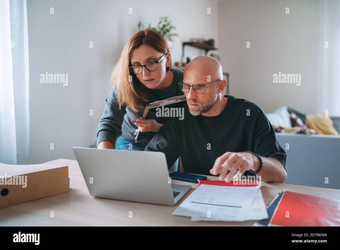 Eigentümer kleiner Unternehmen konzentrierten sich auf die Finanzplanung im Home-Office, die Prüfung von Papieren und die Verwaltung von Online-Aufgaben auf einem Laptop, die Darstellung von Teamarbeit und Reaktionen Stockfoto