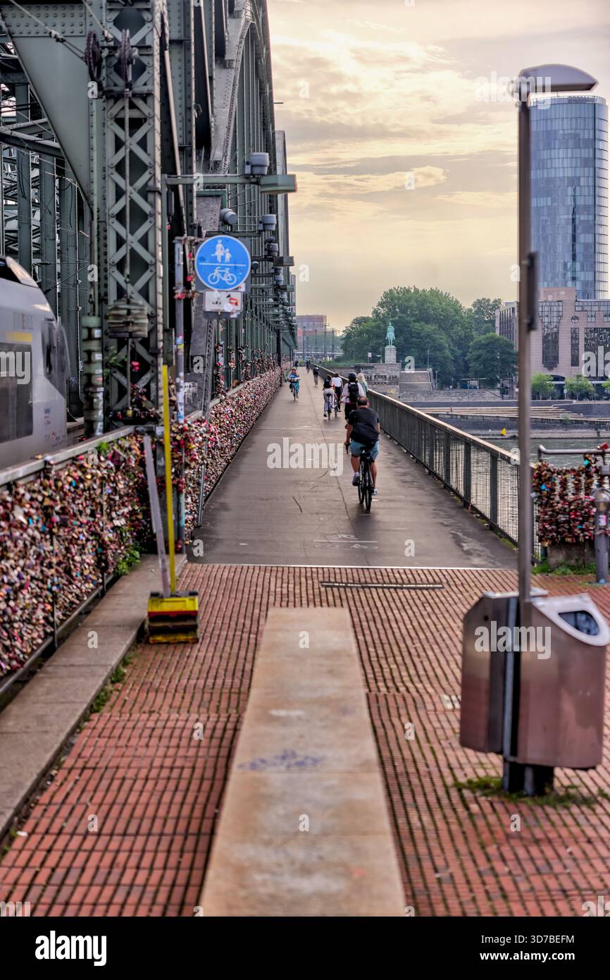 Fußgänger überqueren die Hohenzollernbrücke bei Sonnenaufgang, Köln, Deutschland Stockfoto
