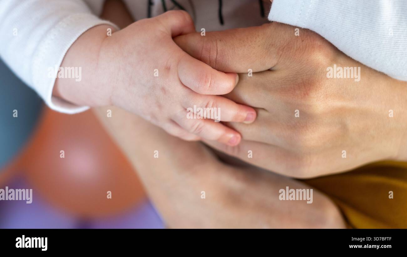 Die Hand eines Kindes hält sanft die Hand eines Erwachsenen, zeigt die Verbindung von Familie und Zweisamkeit und betont die Schönheit des Alterns und gemeinsamer Momente Stockfoto