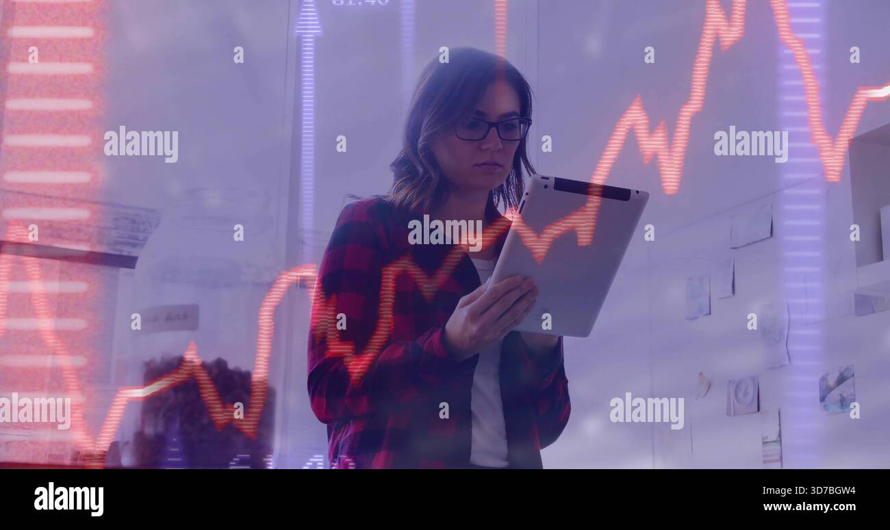 Die Tablettenfrau, die im Büro Aktiendiagramme ansieht, trägt rotes Karo und die Brille hat Notizen hinterlassen Stockfoto