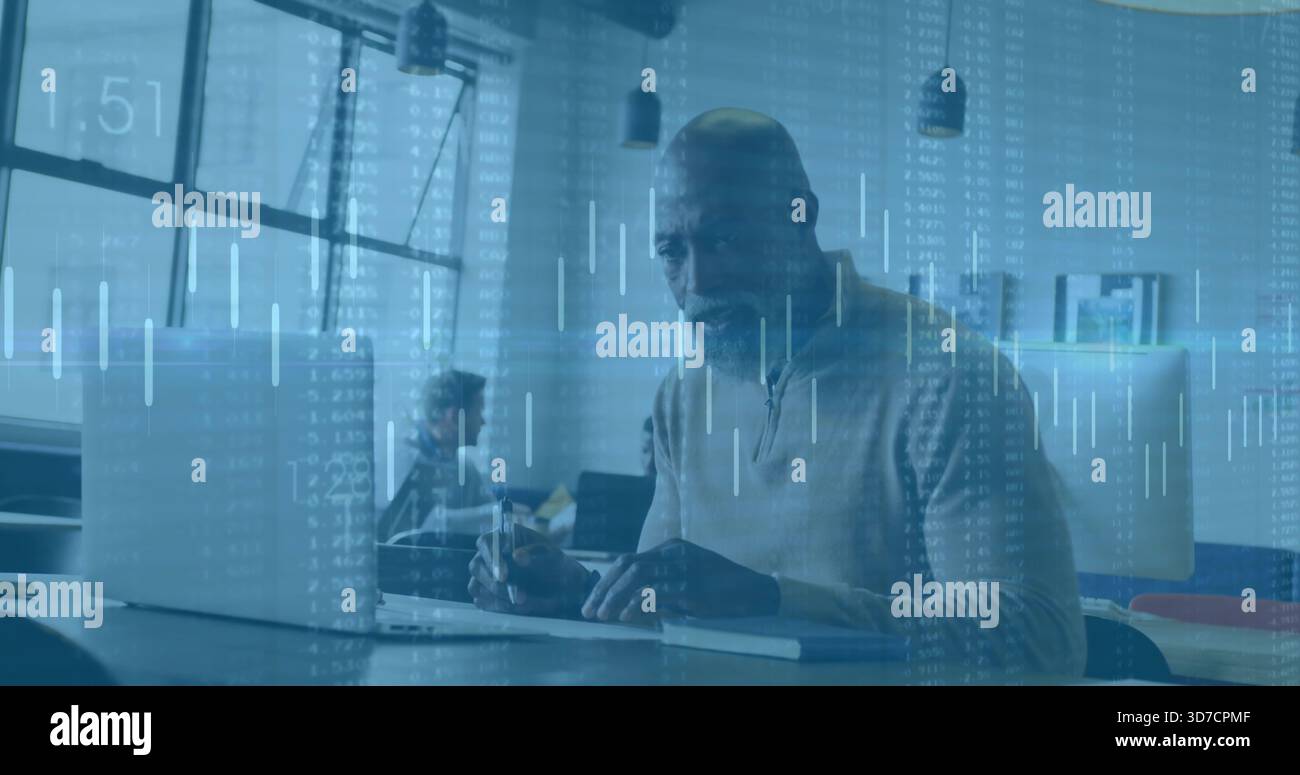 Arbeitender Mann mit Pullover, der auf einem Laptop auf einem modernen Schreibtisch mit Notebook und Daten-Overlay schreibt Stockfoto