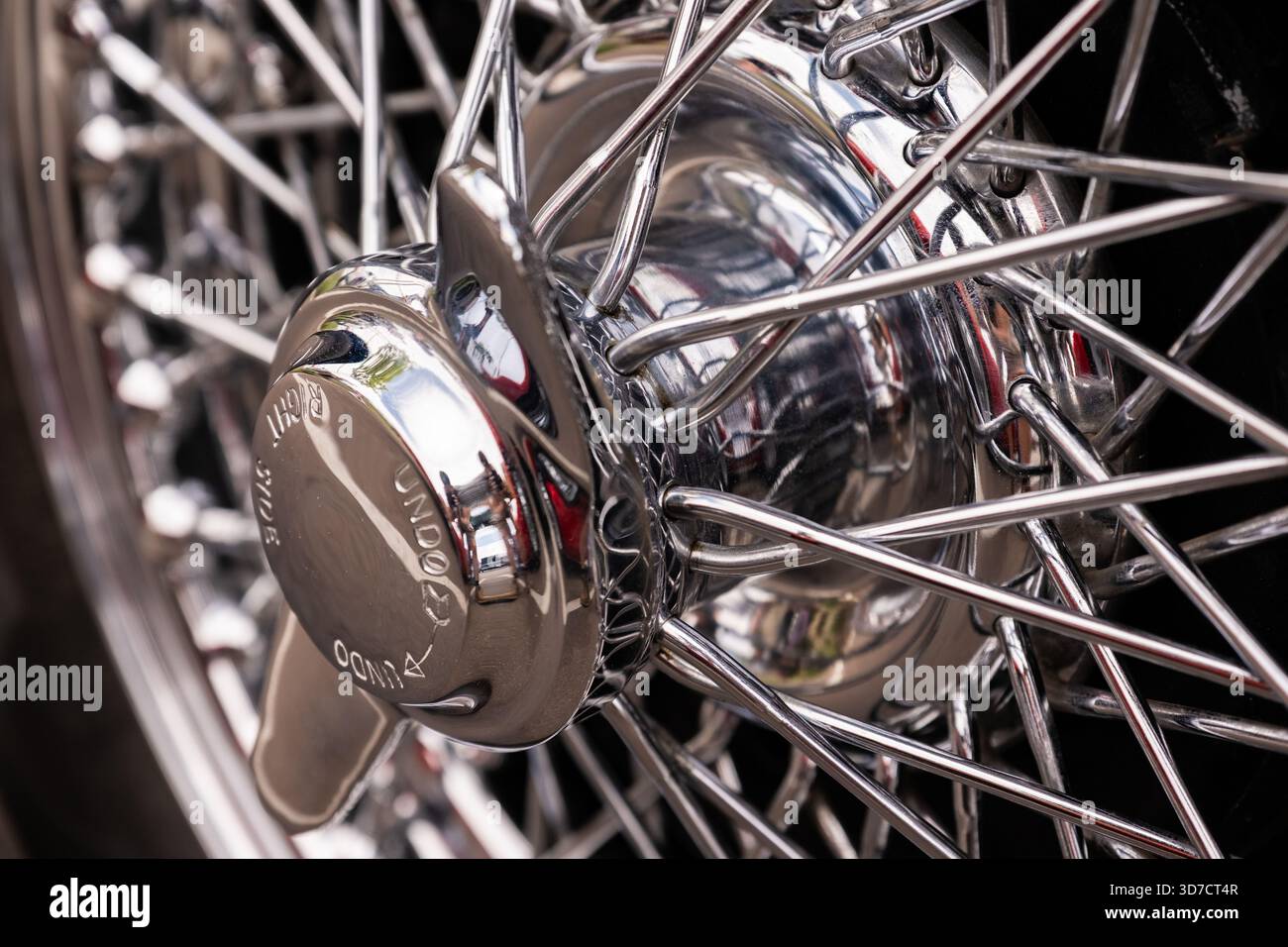 Detaillierte Makroaufnahme des polierten Chromrads eines Oldtimers mit den komplizierten Speichen und der reflektierenden Metalloberfläche. Stockfoto