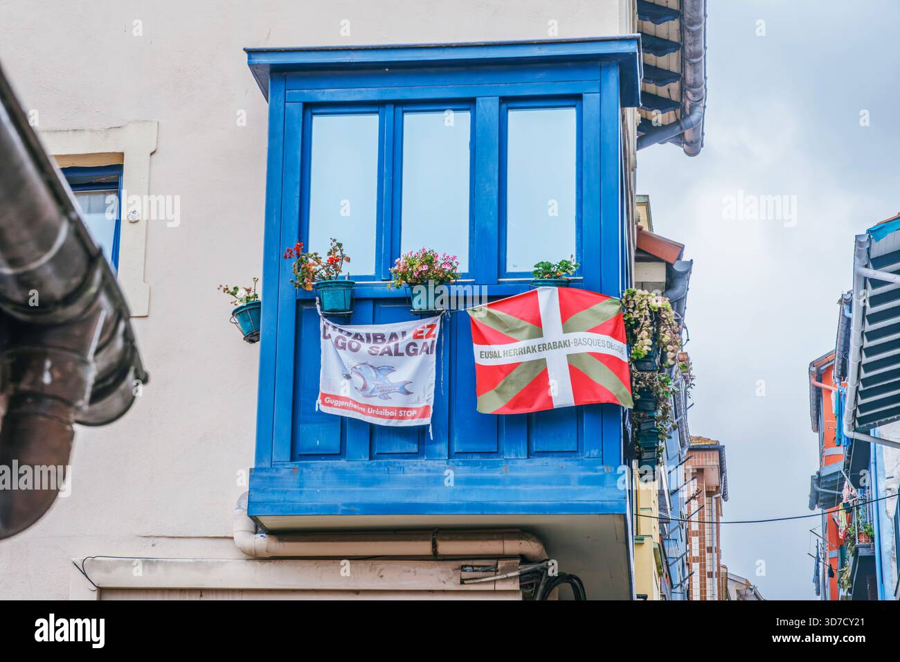 Blauer Balkon mit Ikurrnia-Flagge und Social Protest Banner, Straßenblick auf das traditionelle Gebäude im Baskenland, Spanien Stockfoto
