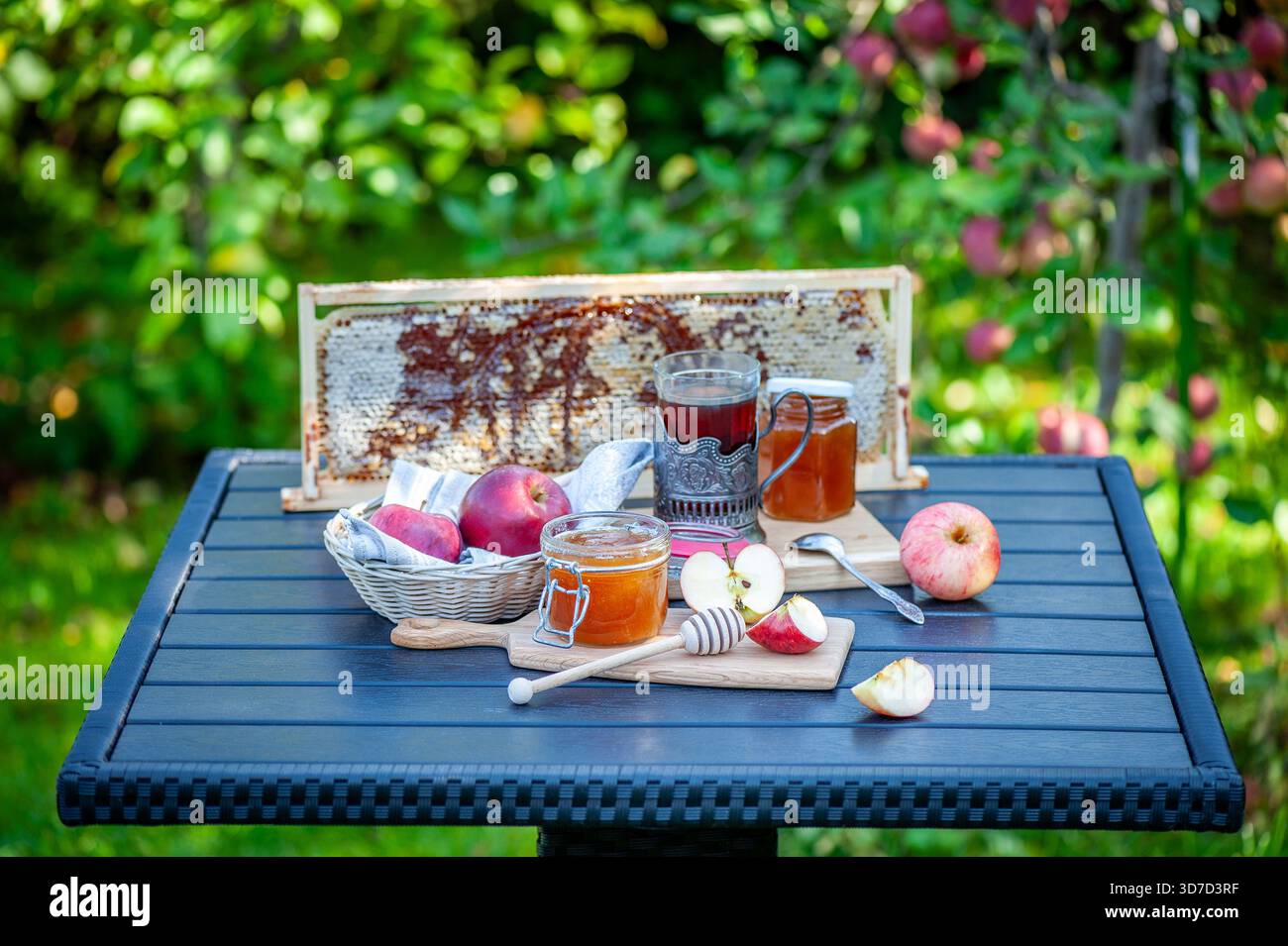 Frische Honigwaben, Äpfel und hausgemachte Marmelade auf dem Tisch im Garten. Natürliches Bio-Frühstück. Stockfoto