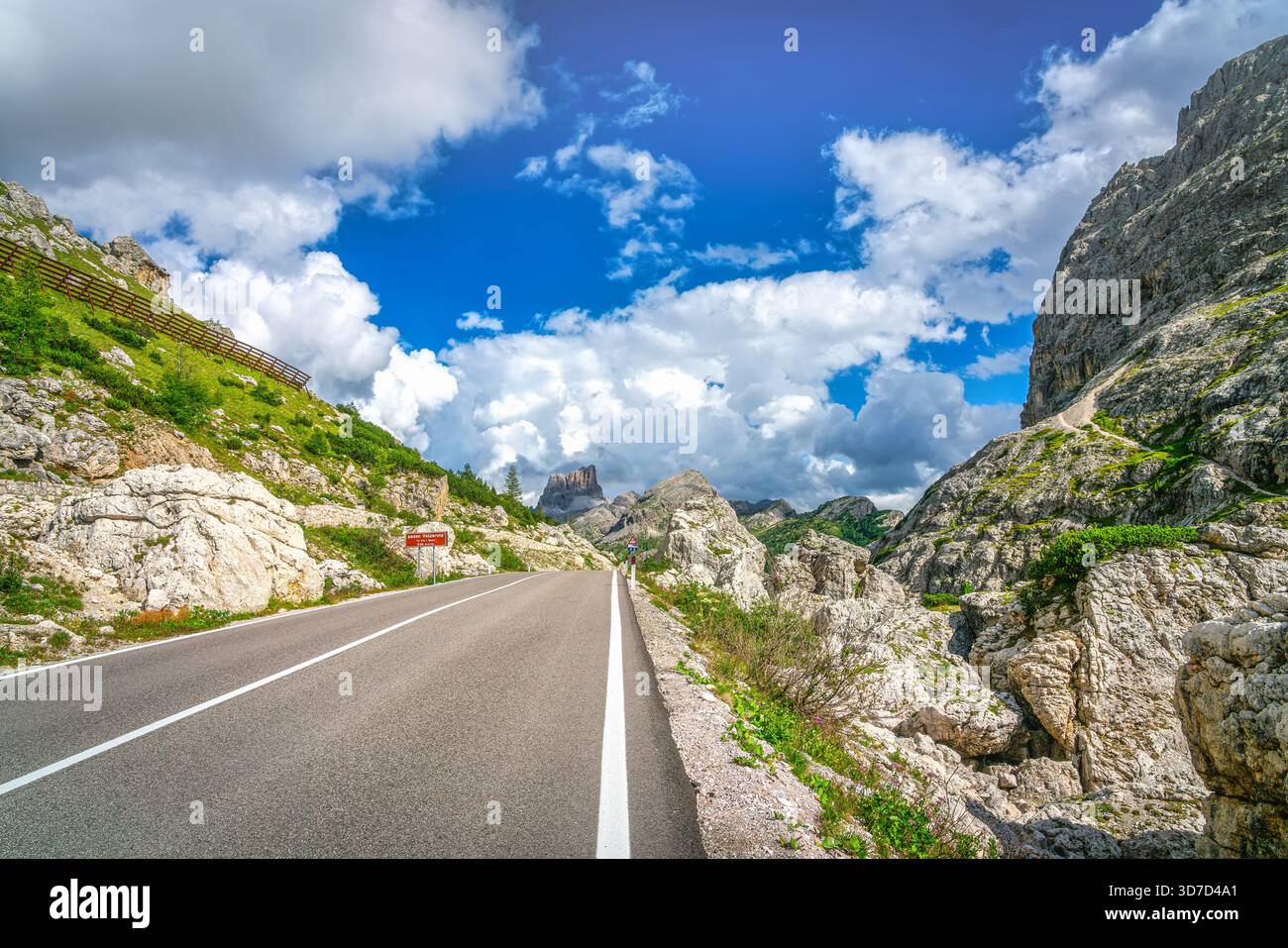 Blick auf die Straße, die durch das felsige Gelände des Valparola-Passes in den italienischen Dolomiten, Belluno, Venetien führt. Zerklüftete Gipfel und Klippen Stockfoto