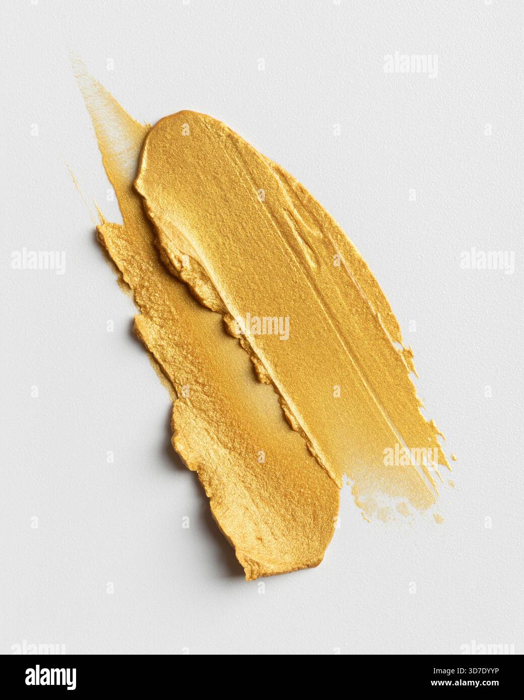 Goldener Farbpigmentabstrich auf weißem Hintergrund. Glänzende metallische Pinselstrichstruktur, geeignet für Kunstprojekte, Designelemente, kreative Hintergründe und Stockfoto