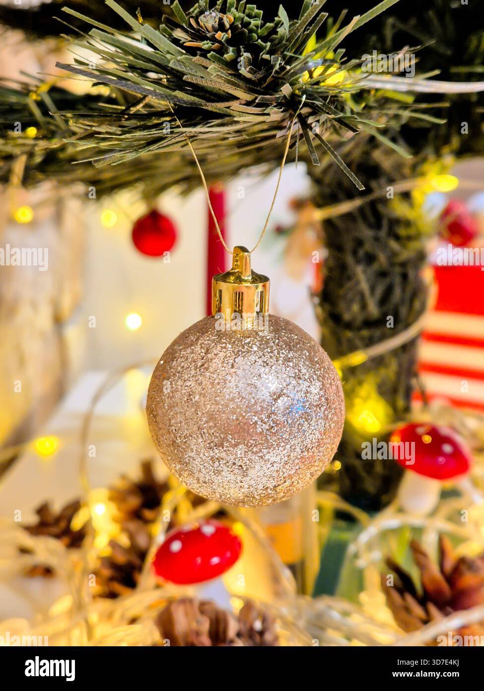 Eine goldene Kugel auf dem Weihnachtsbaum. Festliche Dekoration und eine leuchtende Girlande mit warmem Licht. Stockfoto