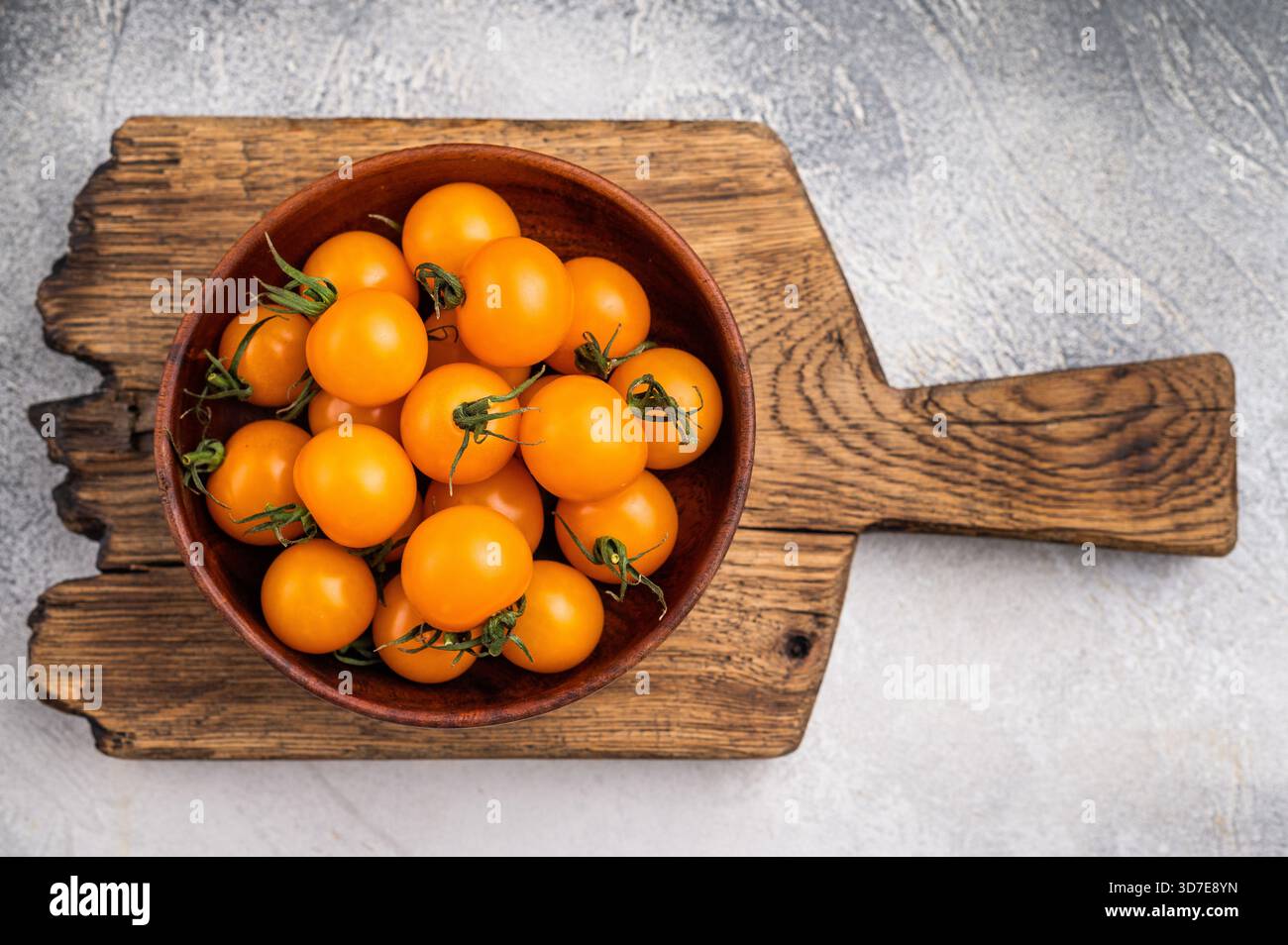 Frische kleine gelbe Kirschtomaten-Sortiment, Mini-Bio-Cocktail-Tomatenmischung. Grauer Hintergrund. Draufsicht. Stockfoto