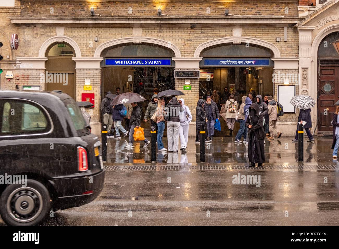 LONDON – 29. OKTOBER 2025: Whitechapel Station E1 – Pendler mit Regenschirmen fahren an regnerischen Herbsttagen aus Stockfoto