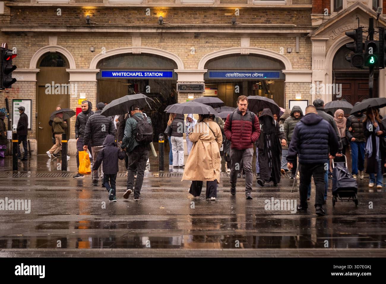 LONDON – 29. OKTOBER 2025: Whitechapel Station E1 – Pendler mit Regenschirmen fahren an regnerischen Herbsttagen aus Stockfoto