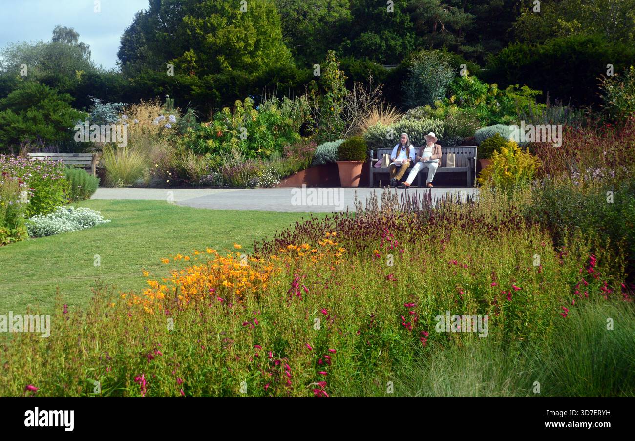 Ältere Ehepaare sitzen auf einer Holzbank und bewundern die Grenzen im RHS Garden Harlow Carr, Harrogate, Yorkshire, England, Großbritannien Stockfoto