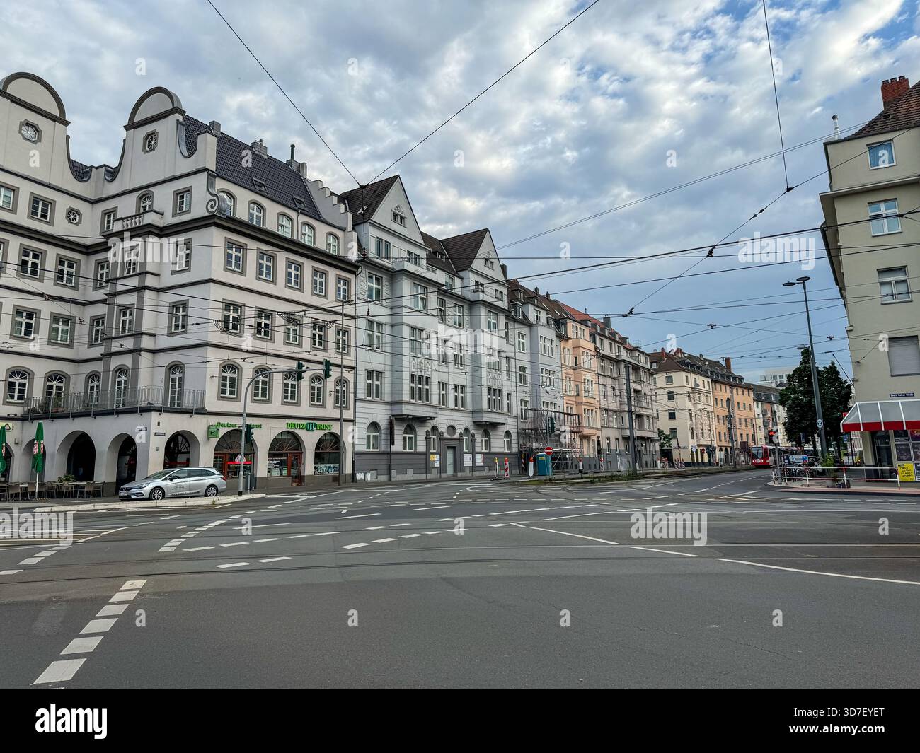 Breite Straße gesäumt von historischen weißen Fassaden und Straßenbahnleitungen in Köln, Deutschland. Stockfoto