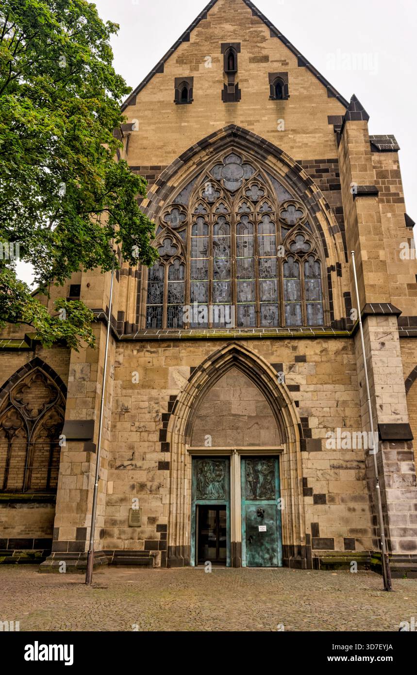Fassade von St. Aposteln in Köln, Deutschland, mit Mauerwerk, gotischen Fenstern und dem Haupteingang. Stockfoto