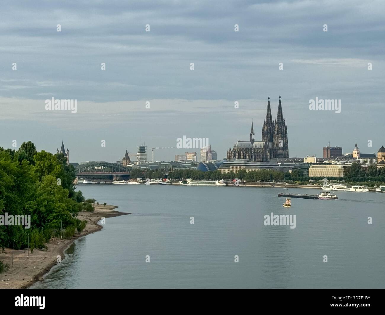 Breiter Blick auf den Rhein in Richtung Kölner Dom und Skyline der Stadt unter weichen Morgenwolken. Stockfoto