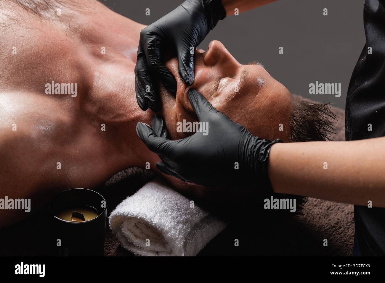 Nahaufnahme eines männlichen Klienten, der eine tiefe bukkale Gesichtsmassage von Therapeuten in Handschuhen erhält Konzept der Skulptur Gesichtsheben und Lymphkurentspannung. Stockfoto