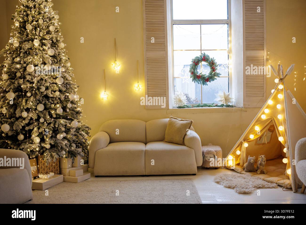 Warmes weihnachtliches Wohnzimmer mit festlichem Baum, Fensterkranz und leuchtendem Kinder Tipi Zelt, perfekte gemütliche Ferienhausinnenhintergrund. Stockfoto