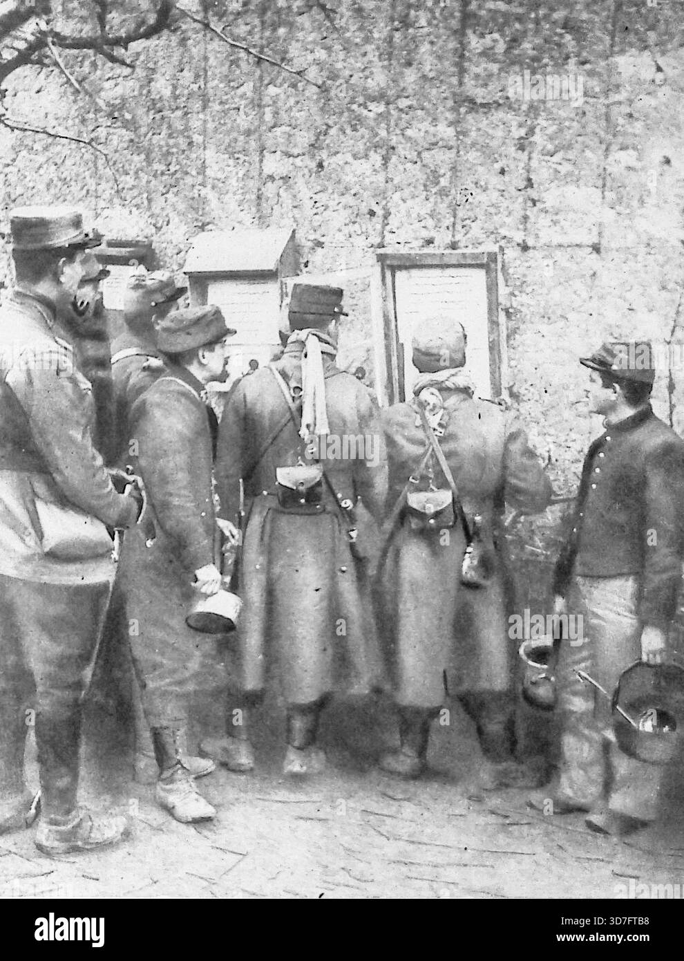 Dieses Foto aus der Ausgabe von Le Miroir vom 7. März 1915 zeigt französische Soldaten, die während des Ersten Weltkriegs in einem „Reportroom“ („Salle des Rapports“) an der Westfront versammelt waren. Die Männer, die sich nur 1.200 Meter von den deutschen Gräben entfernt befinden, lesen offizielle Kommuniqués und Karten. Diese Nachrichten, die täglich von einem Offizier gepflegt und aktualisiert werden, informierten die Truppen über den „langsamen, aber sicheren Fortschritt der alliierten Armeen“. Die Szene zeigt die Bemühungen, die Frontsoldaten während ruhiger Zeiten („heures d'accalmie“) auf dem Laufenden zu halten und den Moralr zu stärken. Stockfoto