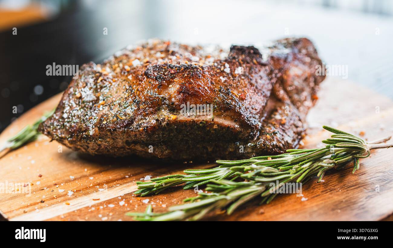 Saftiger ganzer, knochenloser Lammbraten mit Kräutern und Rosmarin auf Holzbrett. Perfekt gewürzt, saftig und bereit zum Schnitzen für besondere Anlässe Stockfoto