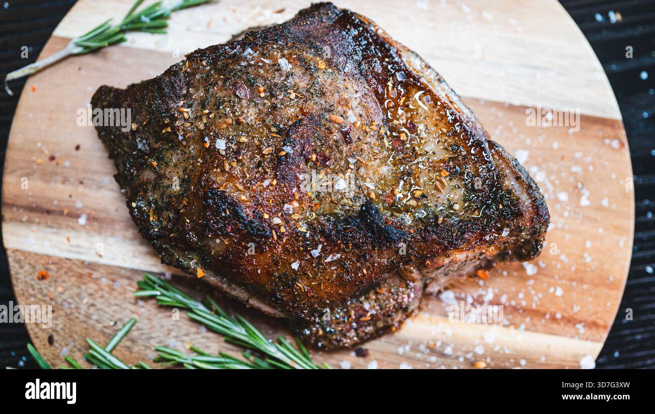 Saftiger ganzer, knochenloser Lammbraten mit Kräutern und Rosmarin auf Holzbrett. Perfekt gewürzt, saftig und bereit zum Schnitzen für besondere Anlässe Stockfoto