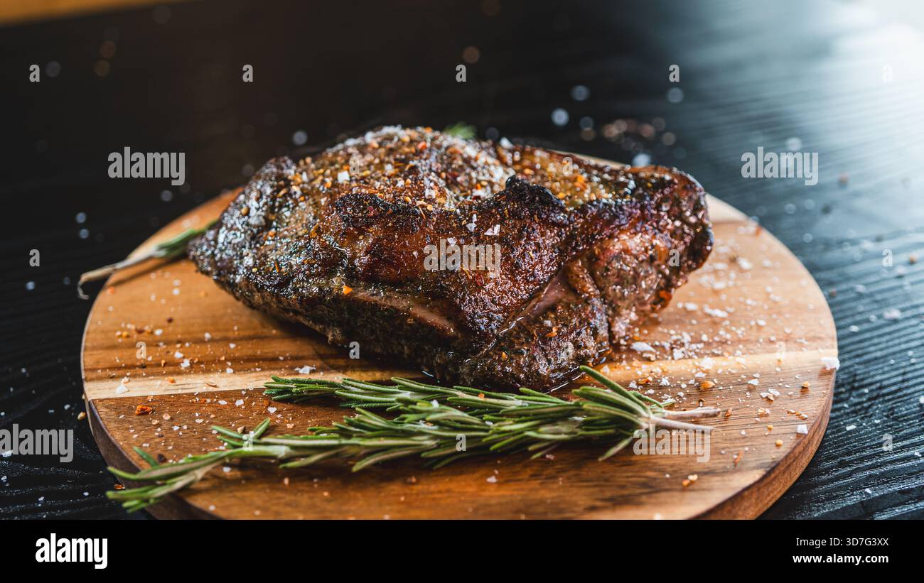 Saftiger ganzer, knochenloser Lammbraten mit Kräutern und Rosmarin auf Holzbrett. Perfekt gewürzt, saftig und bereit zum Schnitzen für besondere Anlässe Stockfoto