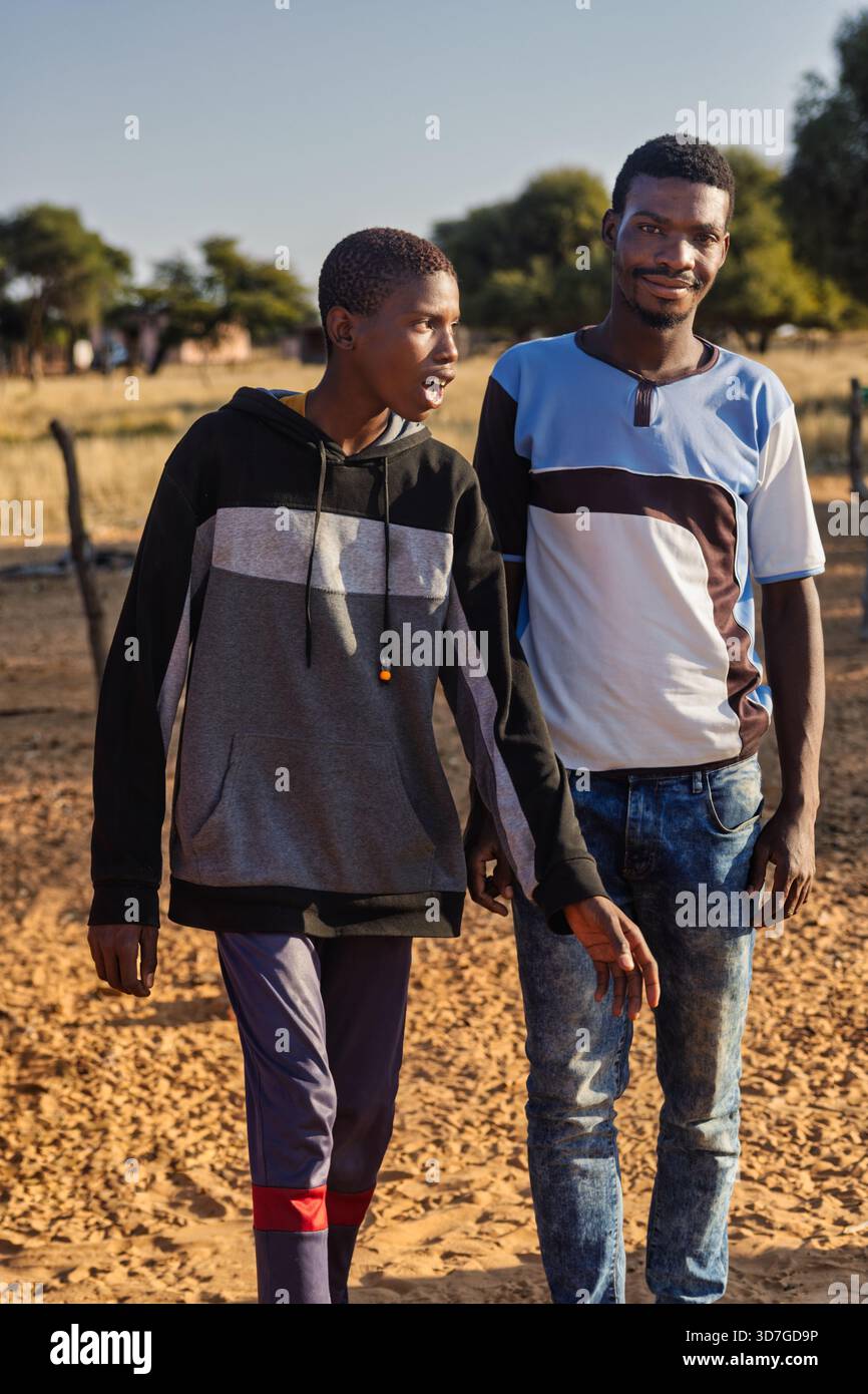 Dorf zwei junge afrikanische Männer, die am Morgen auf dem Weg zur Arbeit reden und im Sand spazieren Stockfoto