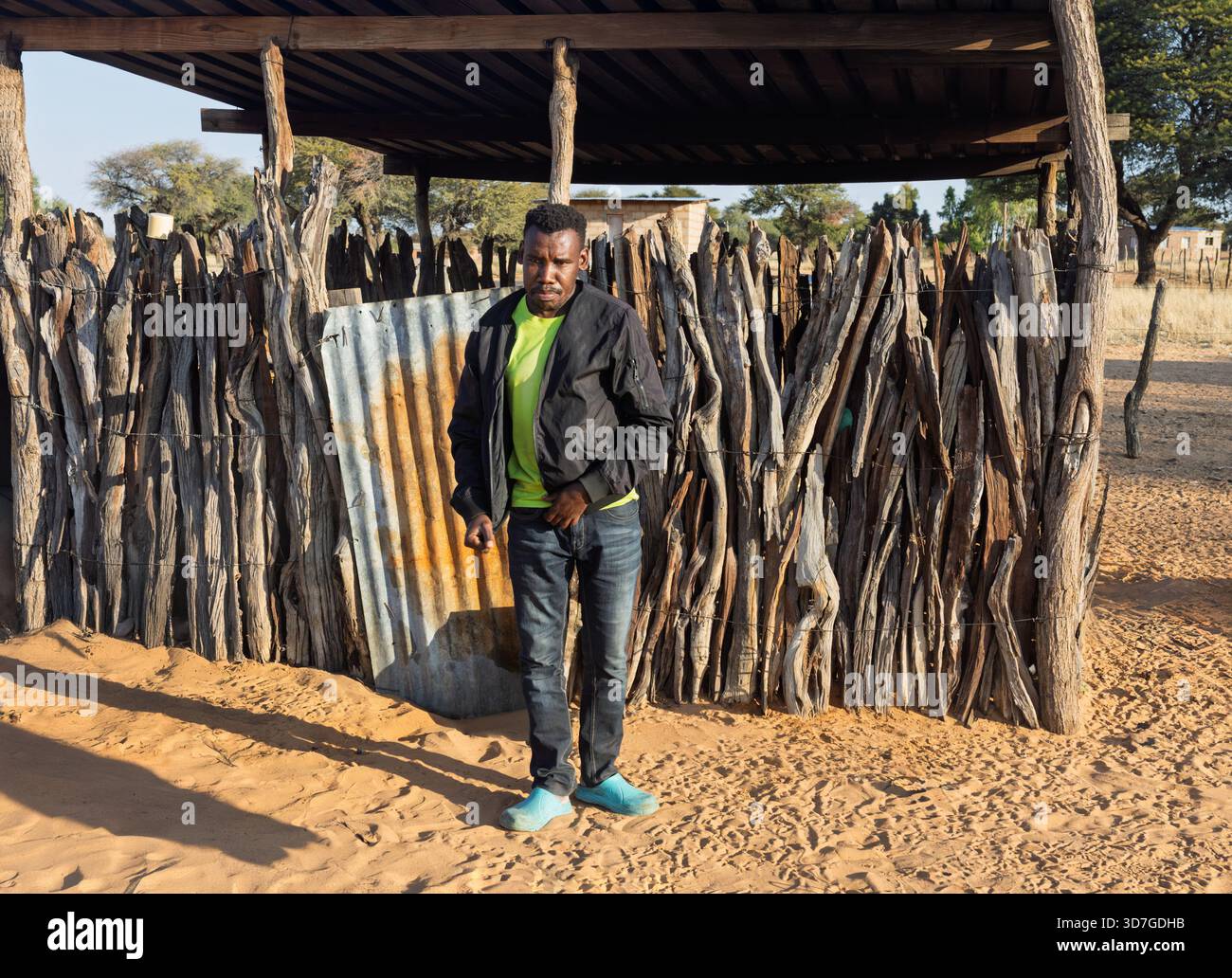 Dorf einzelne afrikanische junge Männer, die vor einer Holzhütte stehen, im Hof Stockfoto
