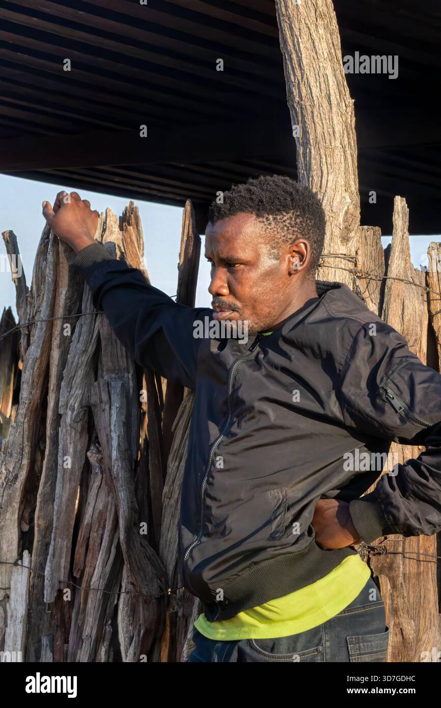 Einzelne afrikanische Dorfmenschen, die vor einer Holzhütte stehen, im Hof Stockfoto