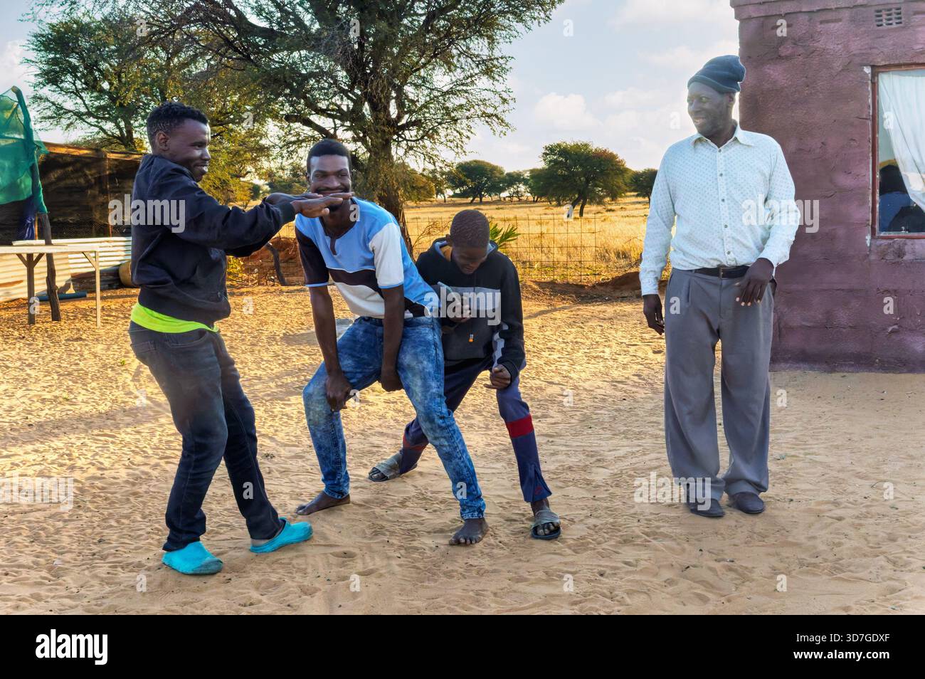 afrikanische Dorfmänner tanzen vor dem Haus im Hof, Familie hat morgens Spaß Stockfoto