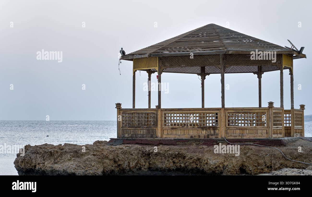 Ein Pavillon am Meer steht auf einem Korallenfelsen in einem ägyptischen Resort mit Blick auf das ruhige Morgenmeer. Stockfoto