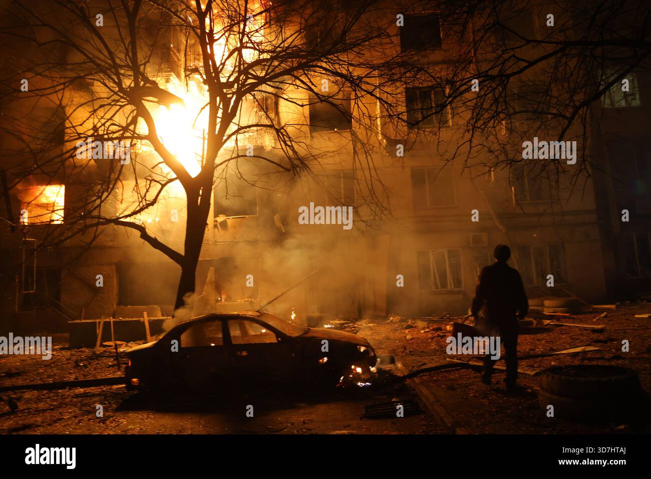 A man walks in front of burning residential building after a Russian attack on Zaporizhzhia, Ukraine, Wednesday, Nov. 26, 2025. (AP Photo/Kateryna Klochko) Stockfoto