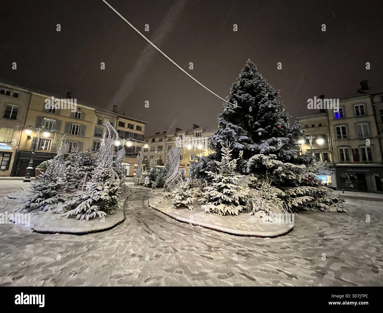 Schneebedeckter Weihnachtsbaum am Place des Vosges in Epinal, Frankreich, am Winterabend, November 2024 - Smartphone-aufgenommenes Stockfoto