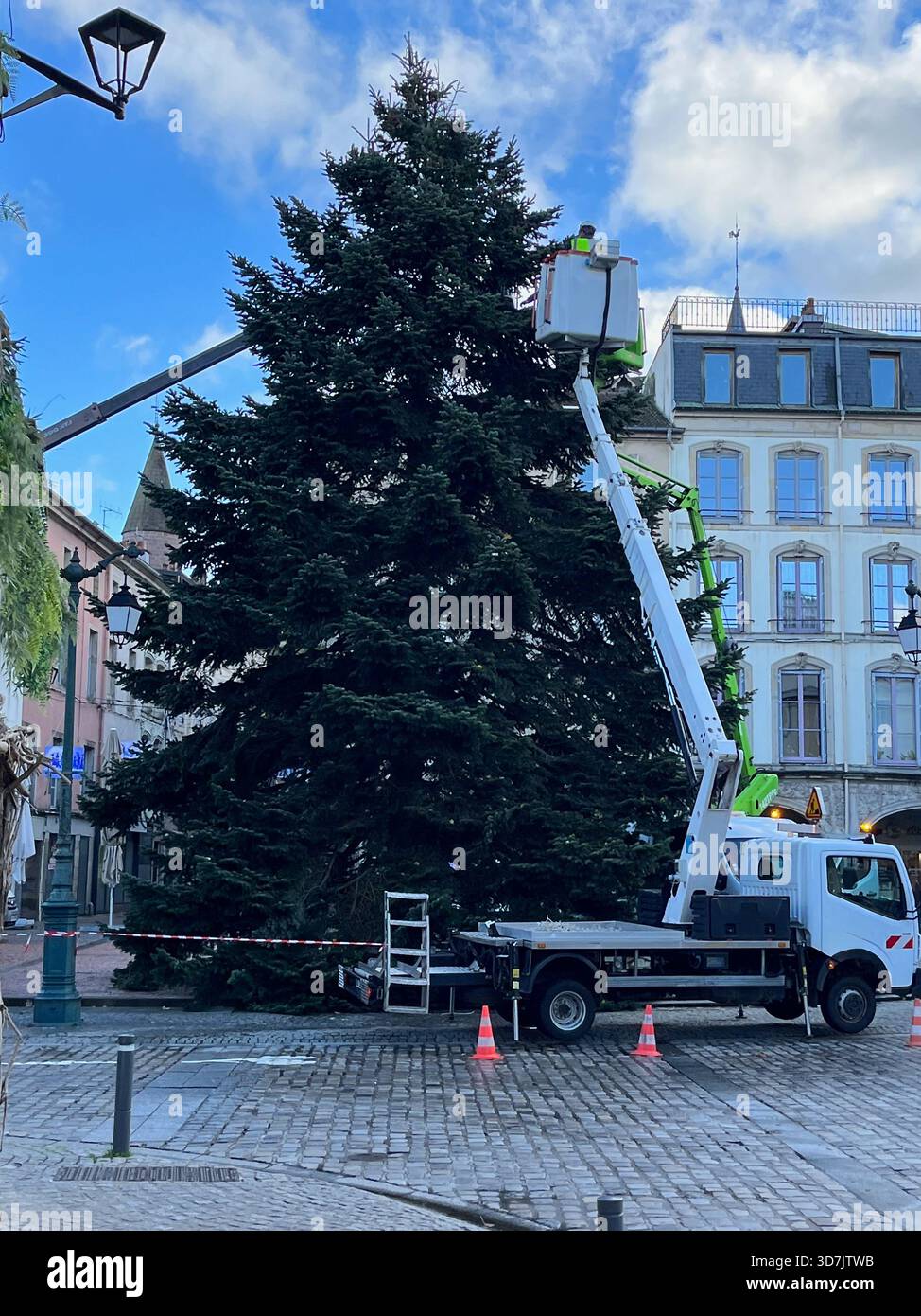 Epinal, Vogesen, Frankreich – 15. November 2023: Ein Gabelstapler und Arbeiter installieren während der Winterferien Dekorationen an einem hohen Weihnachtsbaum - Smartphone-aufgenommenes Stockfoto