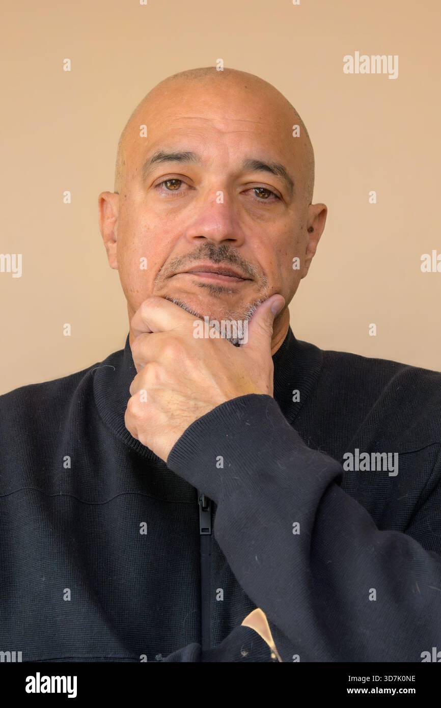 Glatzkopf, der sein Kinn auf seiner Hand in einer nachdenklichen Pose vor neutralem Hintergrund legt. Stockfoto